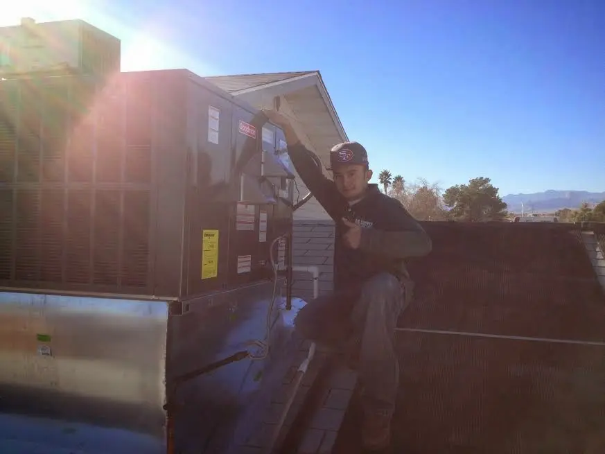 HVAC technician performing AC Tune-Up on a rooftop unit in Cameron